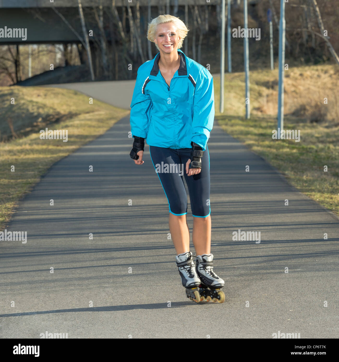 Glückliche Frau Roller skating Sport lächelnd in Park Sonnentag Stockfoto
