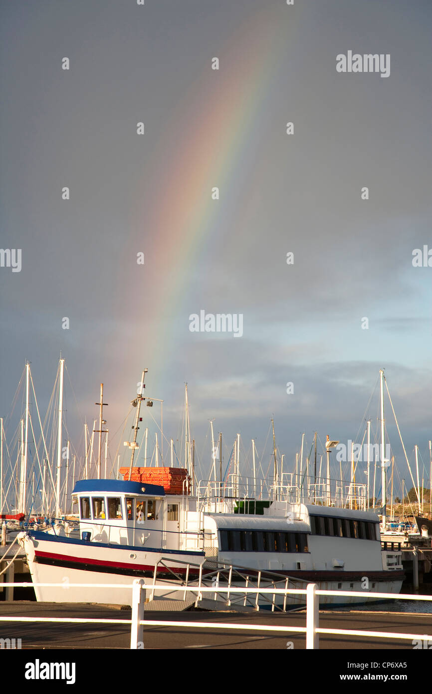 Schöner Regenbogen mit dunklen Himmel und Schiff im Vordergrund bei Geelong Victoria Australia Stockfoto