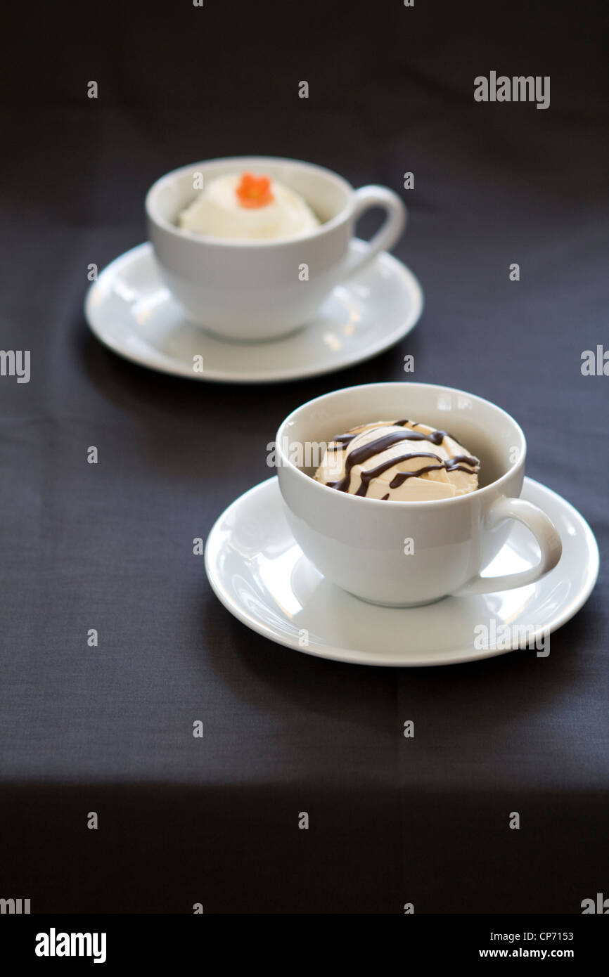 Ein Foto von zwei weißen Tassen mit hausgemachten Muffins auf einem dunklen Hintergrund. Stockfoto