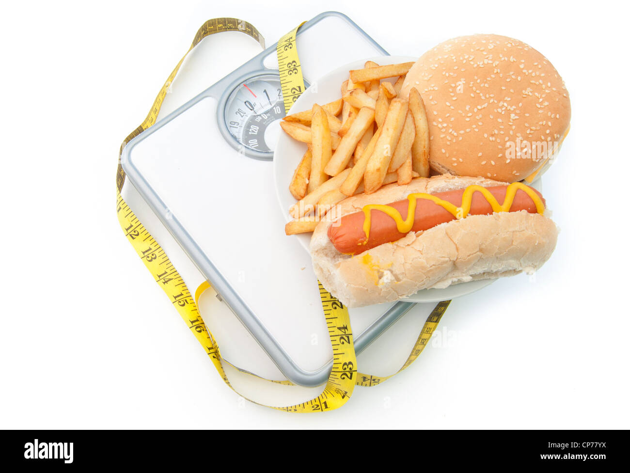 Dickmacher auf Waagen mit einem Maßband, einschließlich Burger Chips und Hot-dog Stockfoto