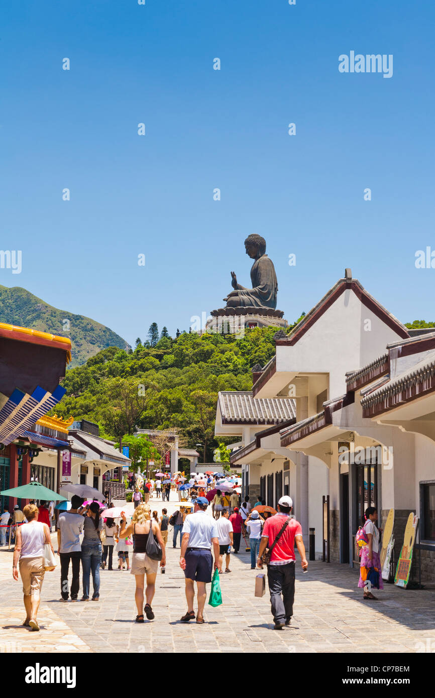 Besucher in der Hauptstraße von Ngong Ping auf Lantau Island, Hong Kong, von der Tian Tan Buddha-Statue dominiert. Stockfoto