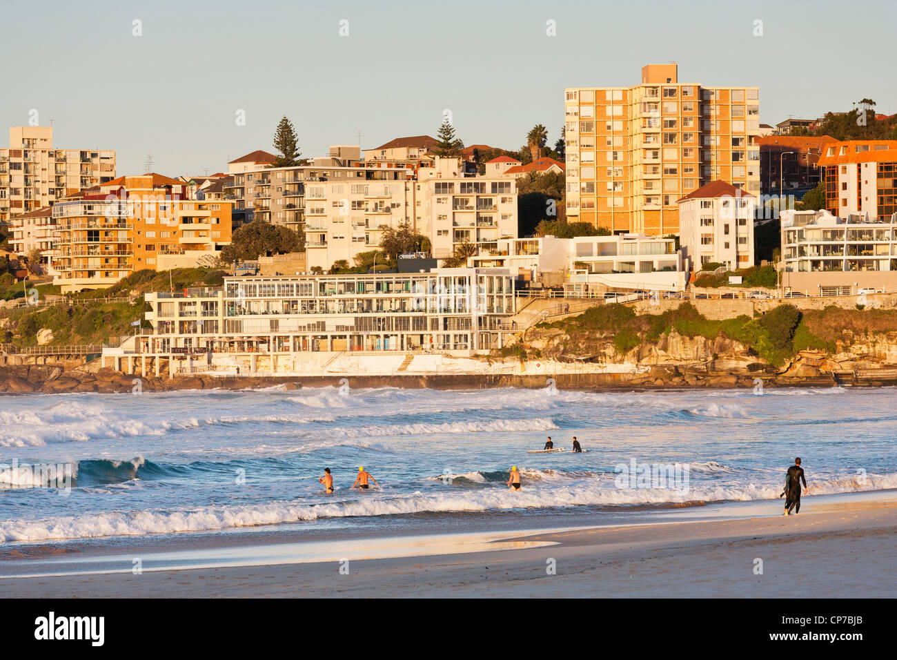 Am frühen Morgen Schwimmer und Surfer am Bondi Beach, Sydney. Mehrfamilienhäuser und Eisberge Club im Hintergrund. Stockfoto