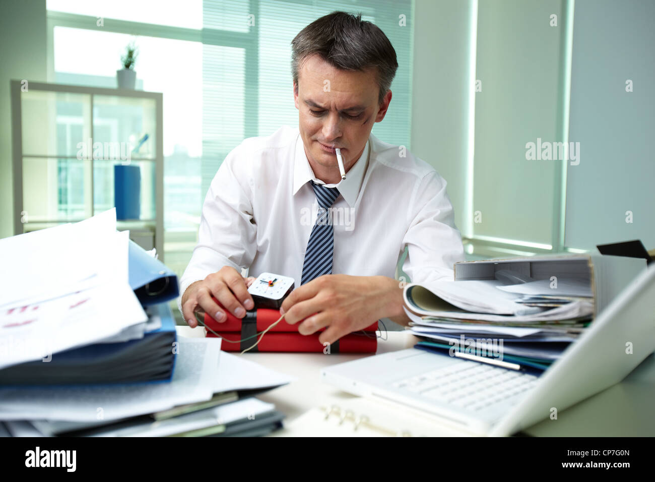 Erfahrener Geschäftsmann, umgeben von großen Haufen Papiere machen Dynamit Stockfoto