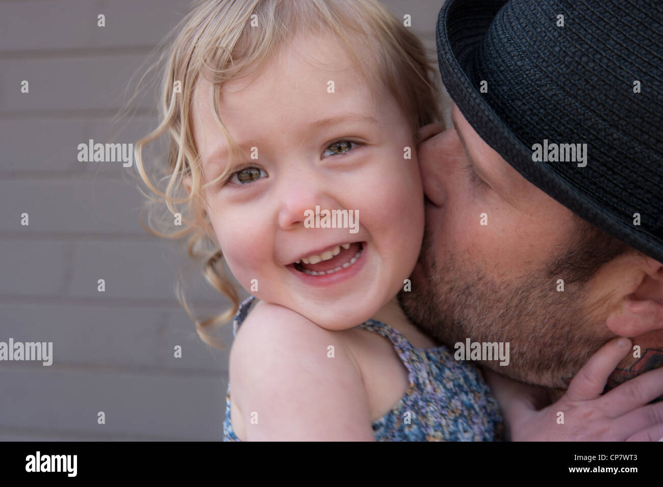 Entzückende 2 jährige Mädchen lacht hautnah wie ihr Vater ihren Hals küsst. Stockfoto