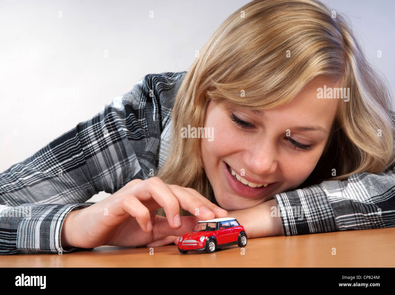 Junge hübsche Frau mit einem Modellauto als Symbol für den Traum von ihrem eigenen Auto. Stockfoto
