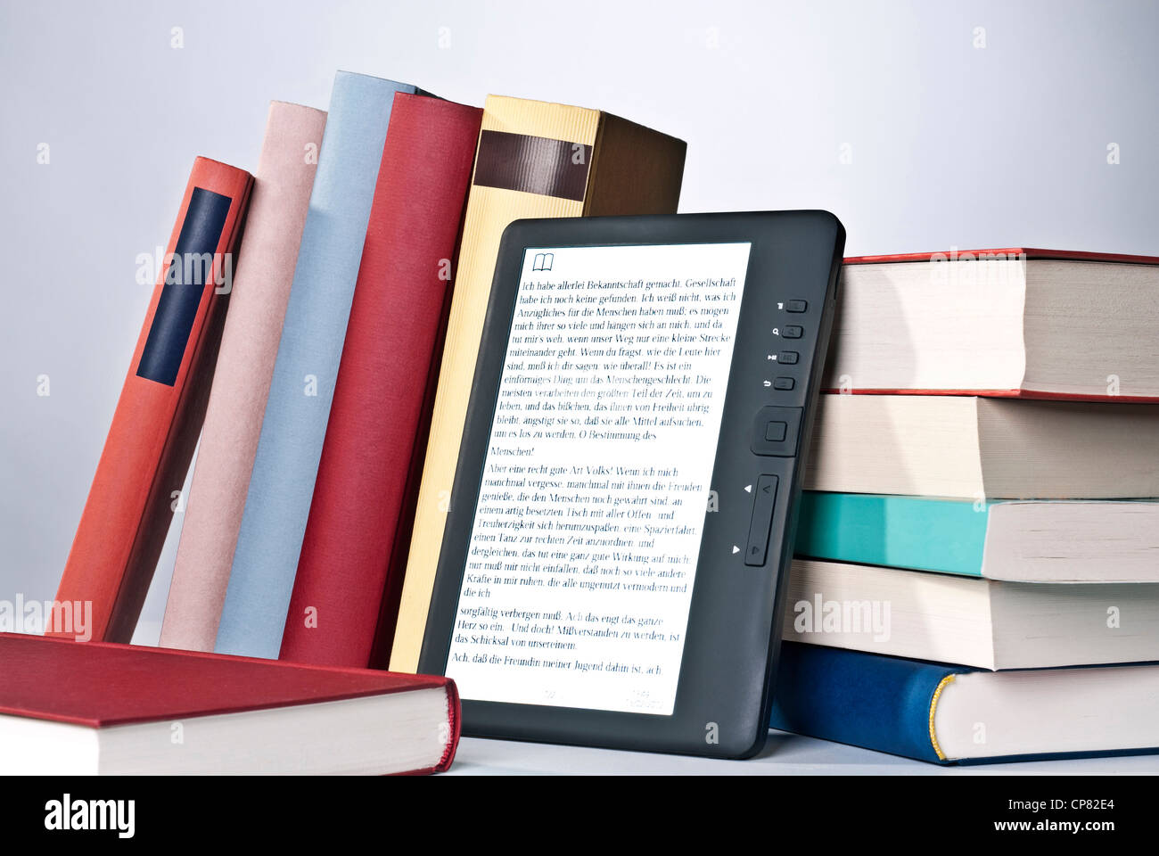 E-Book-Reader und eine Reihe von gedruckten Büchern. Stockfoto