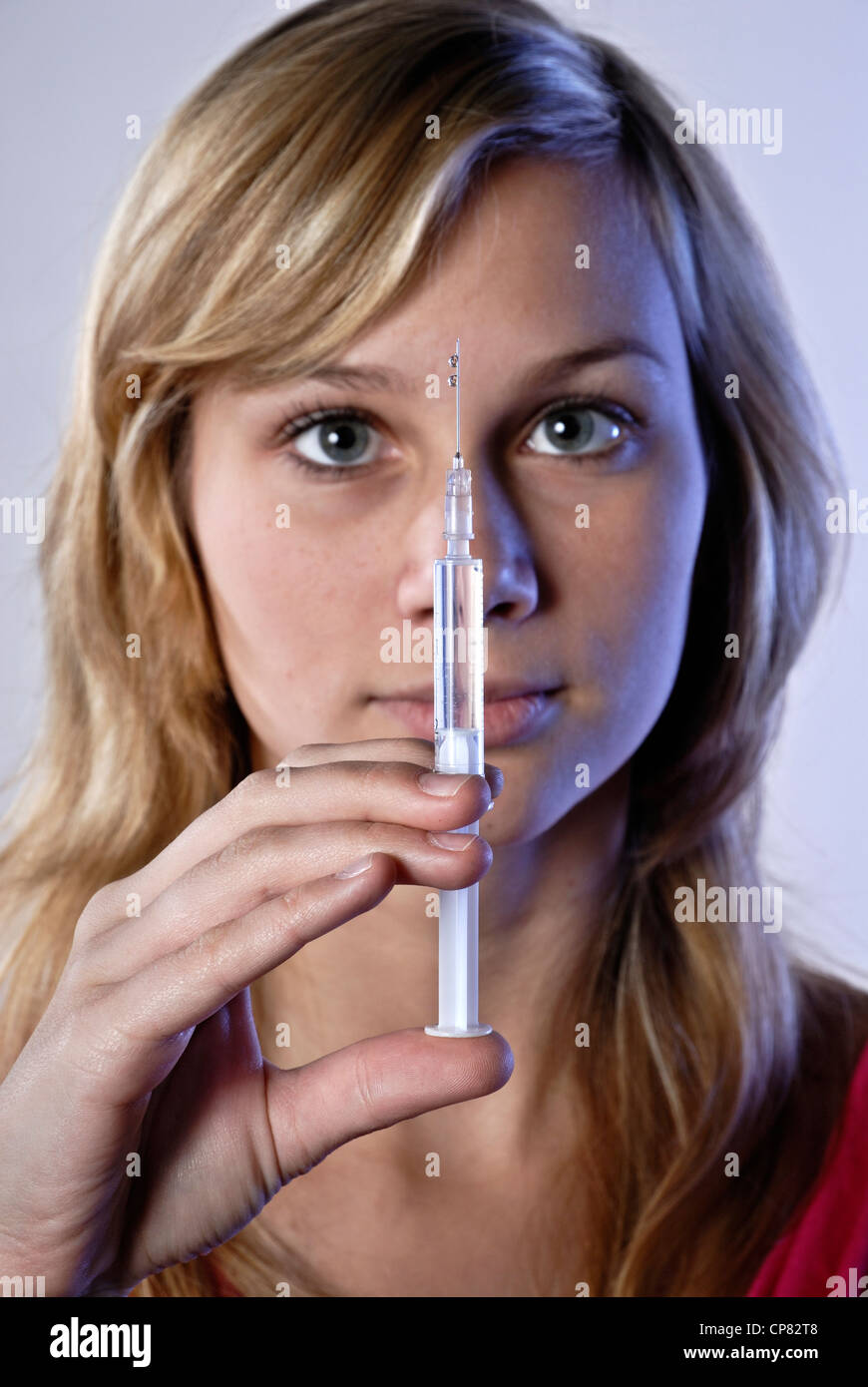 Junge Frau mit Spritze als Symbol für Drogenabhängigkeit. Stockfoto