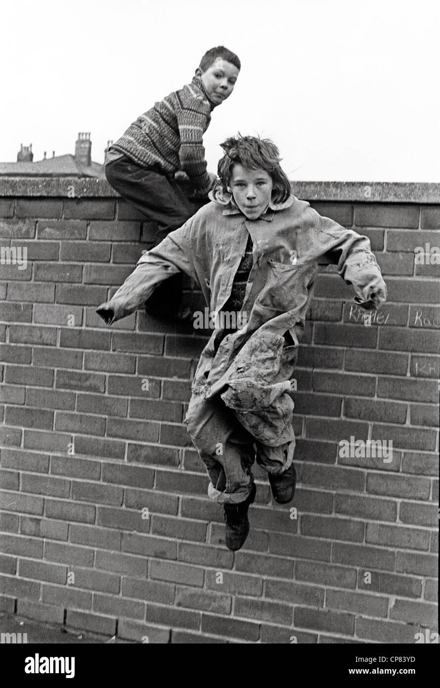 Jungen Schwänzen Kinder klettern über die Mauer in Liverpool Stockfoto