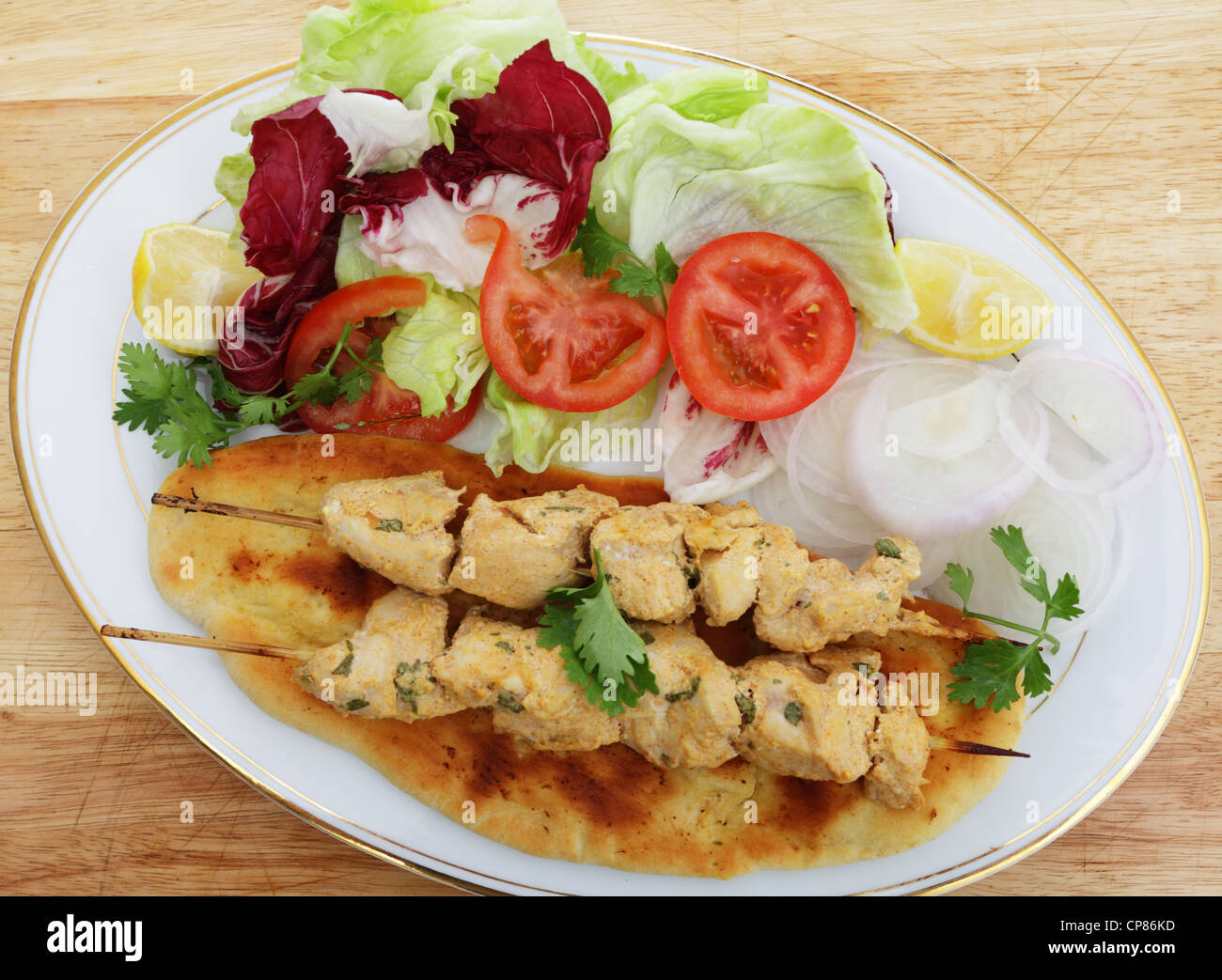 Chicken Tikka Spieße serviert auf hausgemachtem Naan Fladenbrot mit Salat Stockfoto