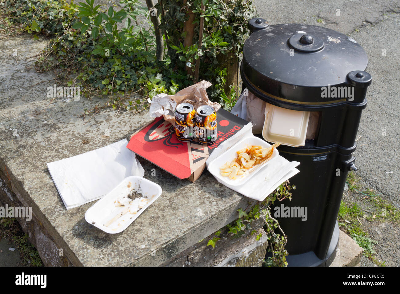 Fast-Food-Abfall und Müll neben einem vollen Abfallbehälter Stockfoto