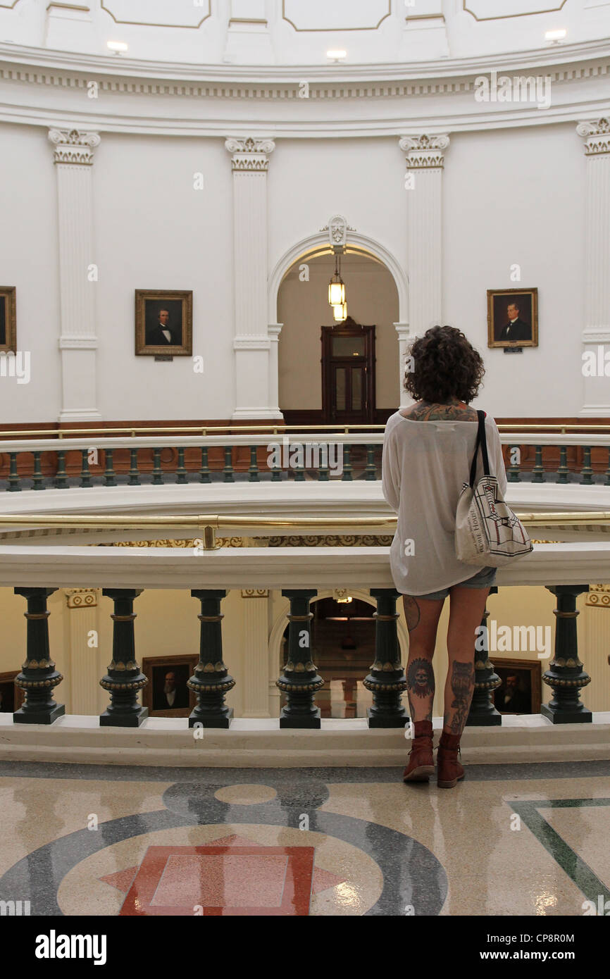 Eine Frau mit Tätowierungen auf ihren Rücken und Beine sieht über die Texas Capitol Rotunde, Austin, Texas Stockfoto