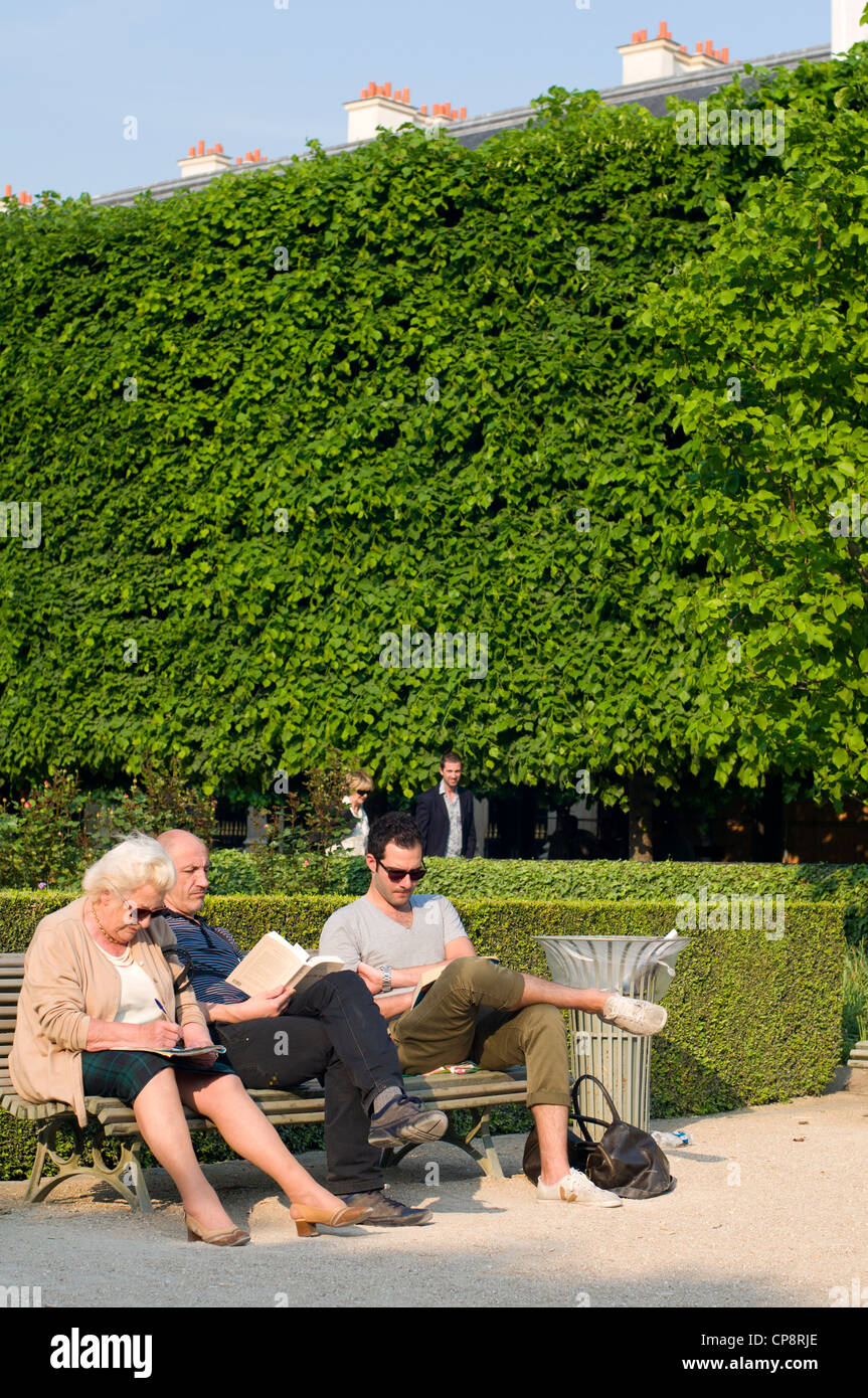 Menschen lesen und entspannen auf einer Parkbank im Jardin du Palais Royal, Paris, Frankreich Stockfoto