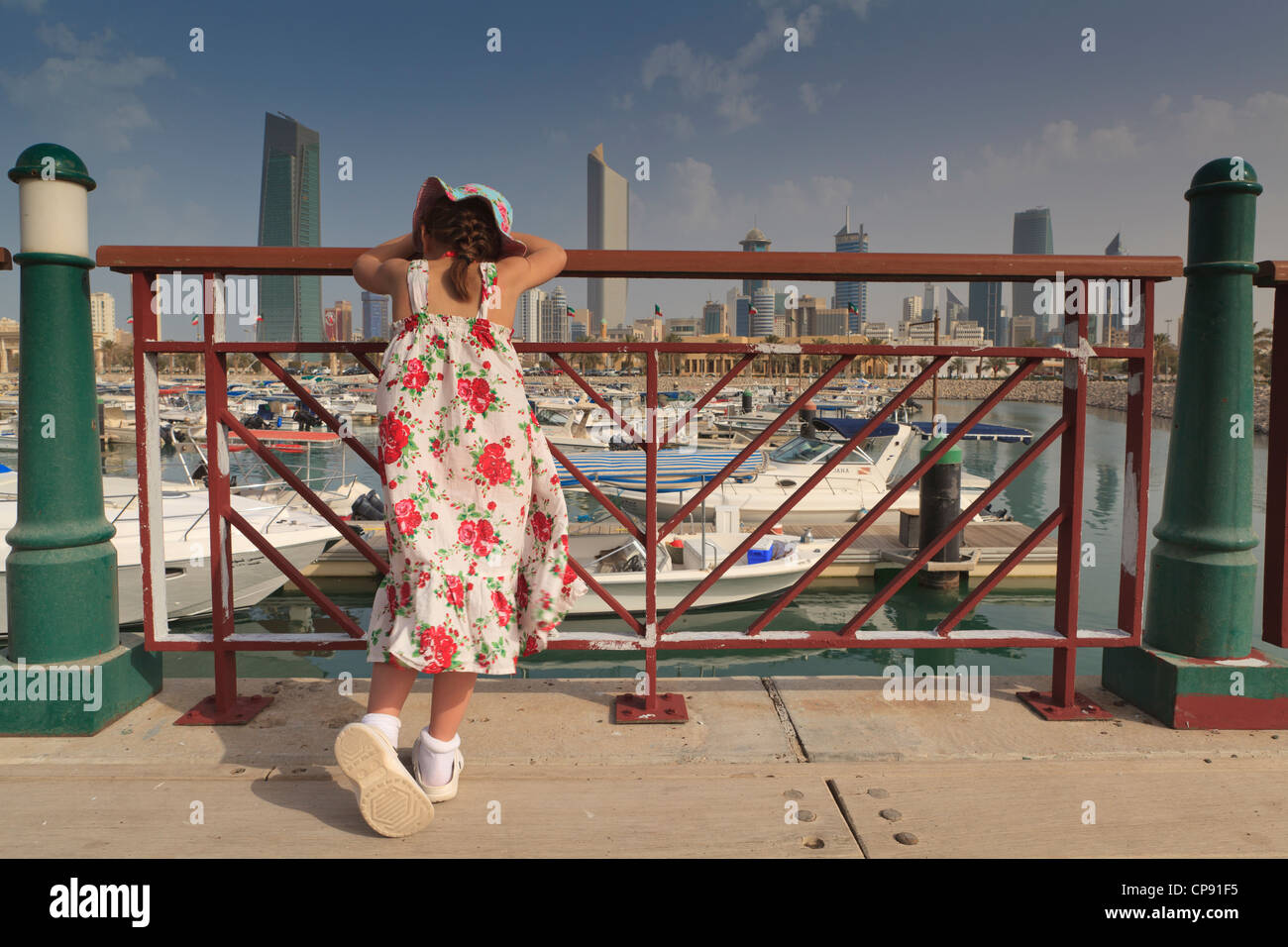 Ein müdes junge Mädchen ruht auf dem Geländer und sieht in der Marina und Kuwait City Skyline vom Souq Sharq Stockfoto
