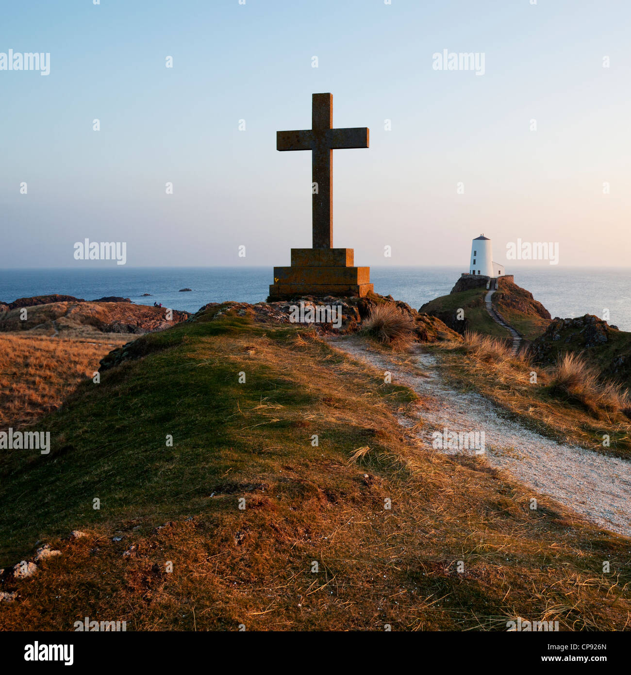 Blick auf das Meer von Llandwyn Insel mit einem Kreuz im Vordergrund und ein Leuchtturm in der Ferne. Stockfoto
