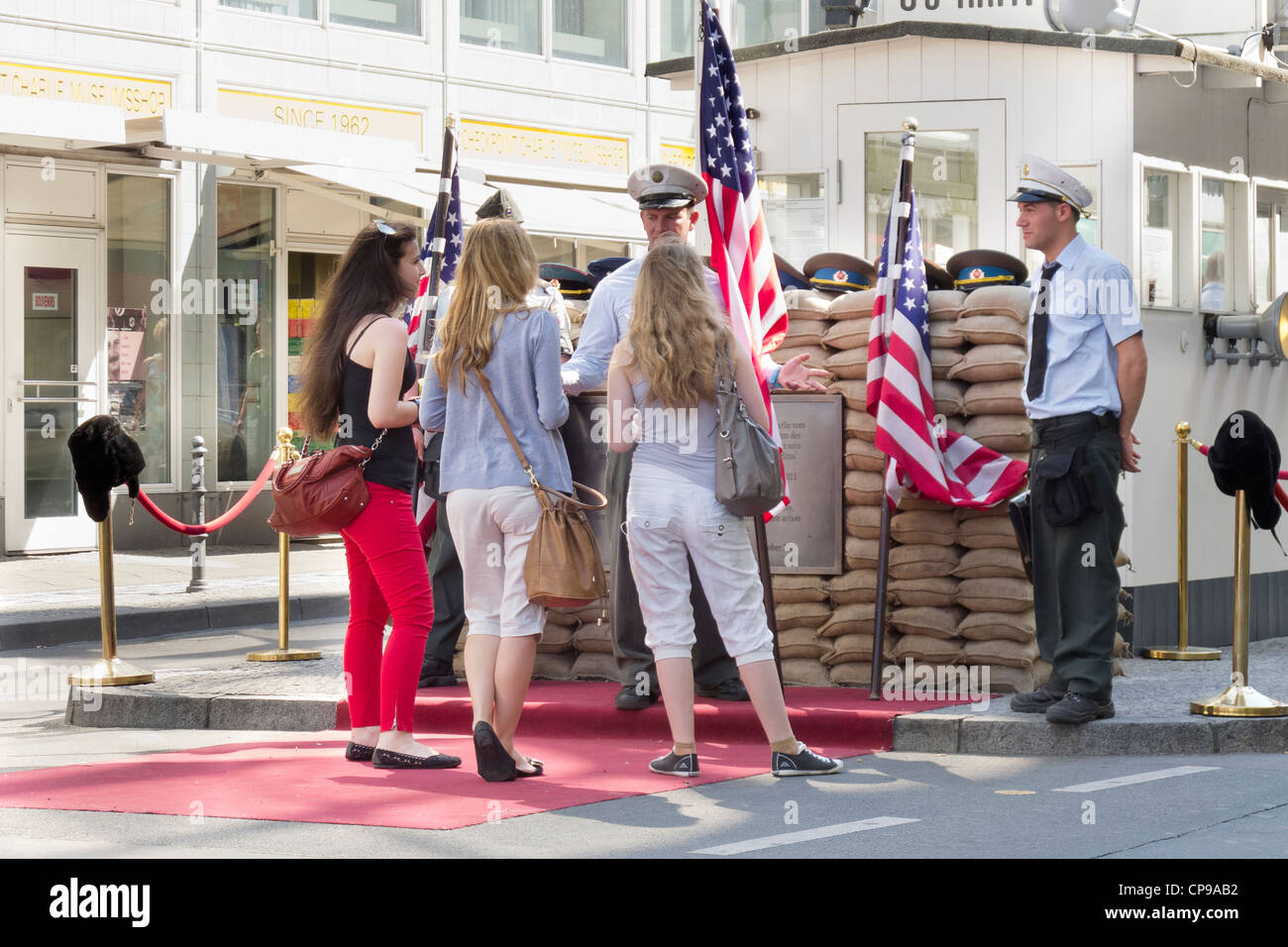 Checkpoint Charlie in der Friedrichstraße - Berliner Mauer mit weiblichen Touristen bekommen ihr Foto mit wachen Stockfoto