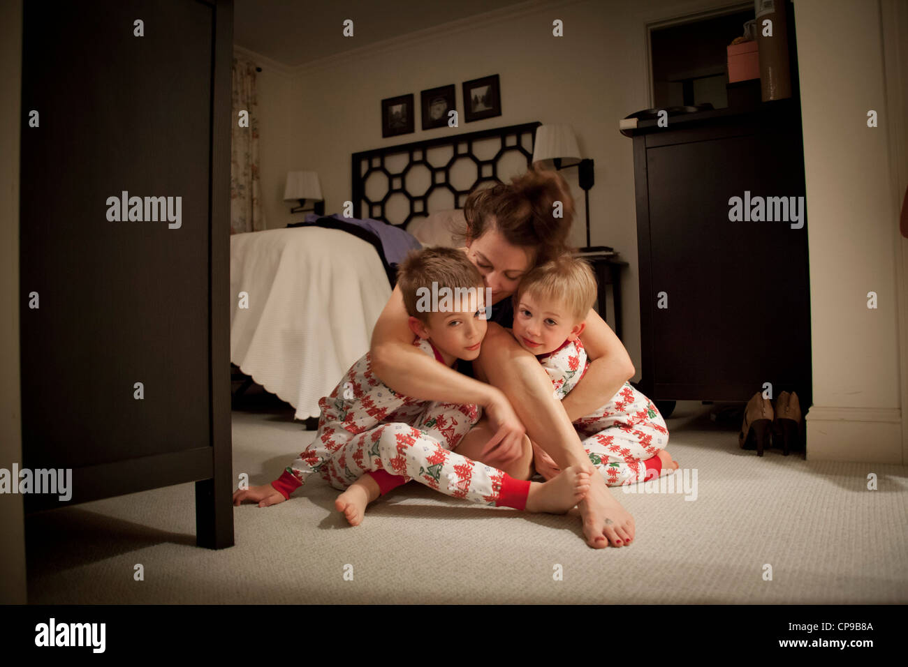 Mutter umarmen zwei Söhne im Pyjama Stockfoto