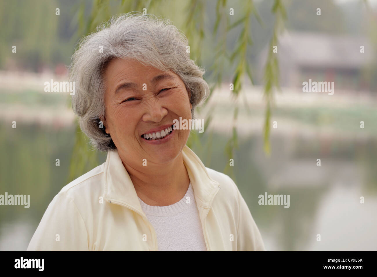 Schuss in den Kopf der älteren Frau lächelnd unter einem Baum Stockfoto