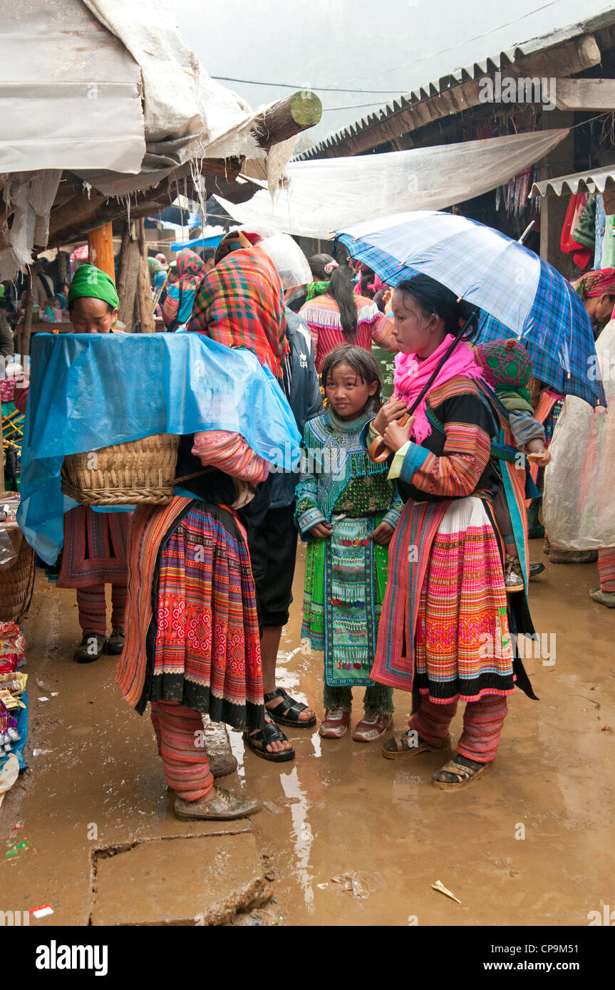 Flower Hmong Familie Unterschlupf unter Sonnenschirmen bei Regen bei Muong Khuong Markt Nord-Vietnam Stockfoto