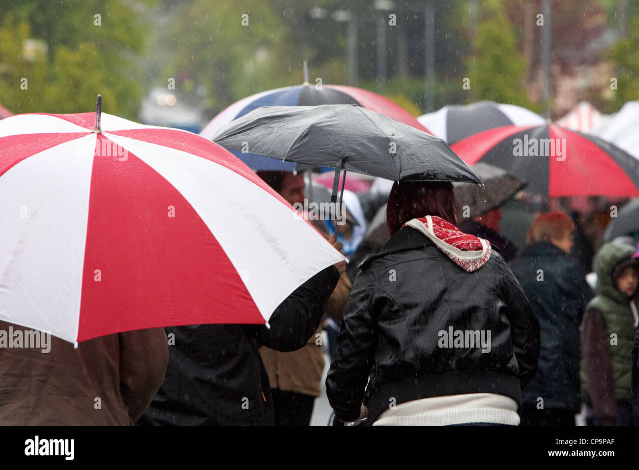 Menschen Sie tragen Regenschirme zu Fuß durch die Stadt im Regen Nordirland Vereinigtes Königreich Stockfoto