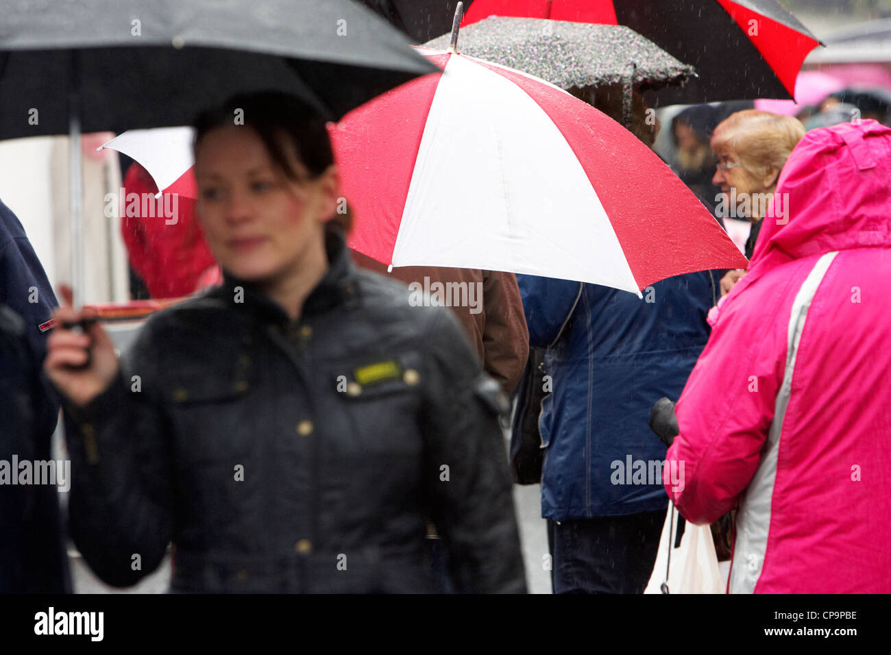 Menschen Sie tragen Regenschirme zu Fuß durch die Stadt im Regen Nordirland Vereinigtes Königreich Stockfoto