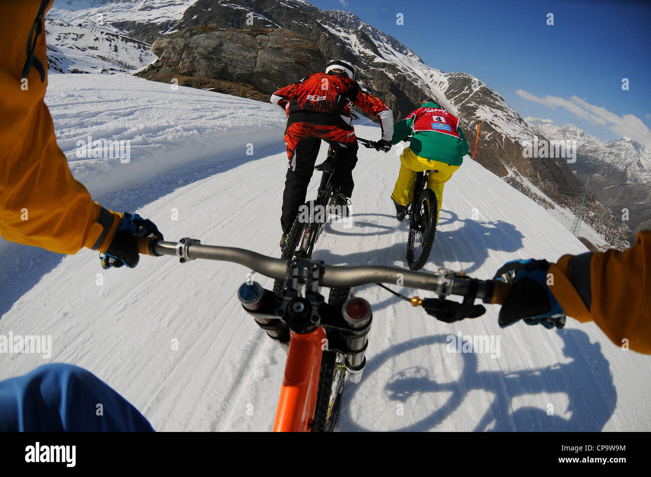 Ein Mountainbiker fährt bergab Hügel auf Schnee mit einer on-Board-Kamera nach zwei weitere Fahrer. Stockfoto