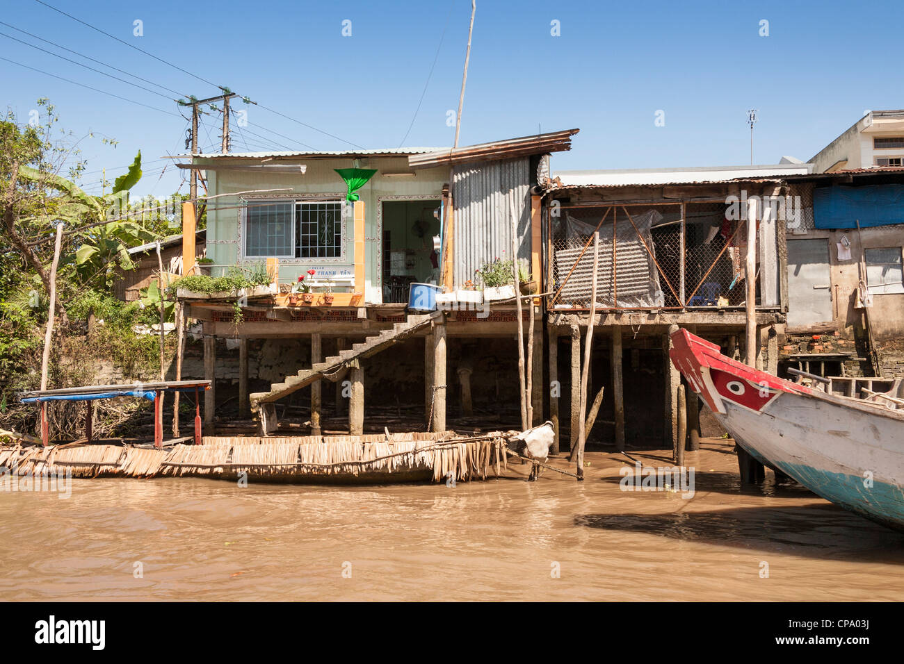 Riverside Häuser unterstützt von Stelzen, in der Nähe von Cai Be und Vinh Long, Mekong-Fluss-Delta, Vietnam Stockfoto