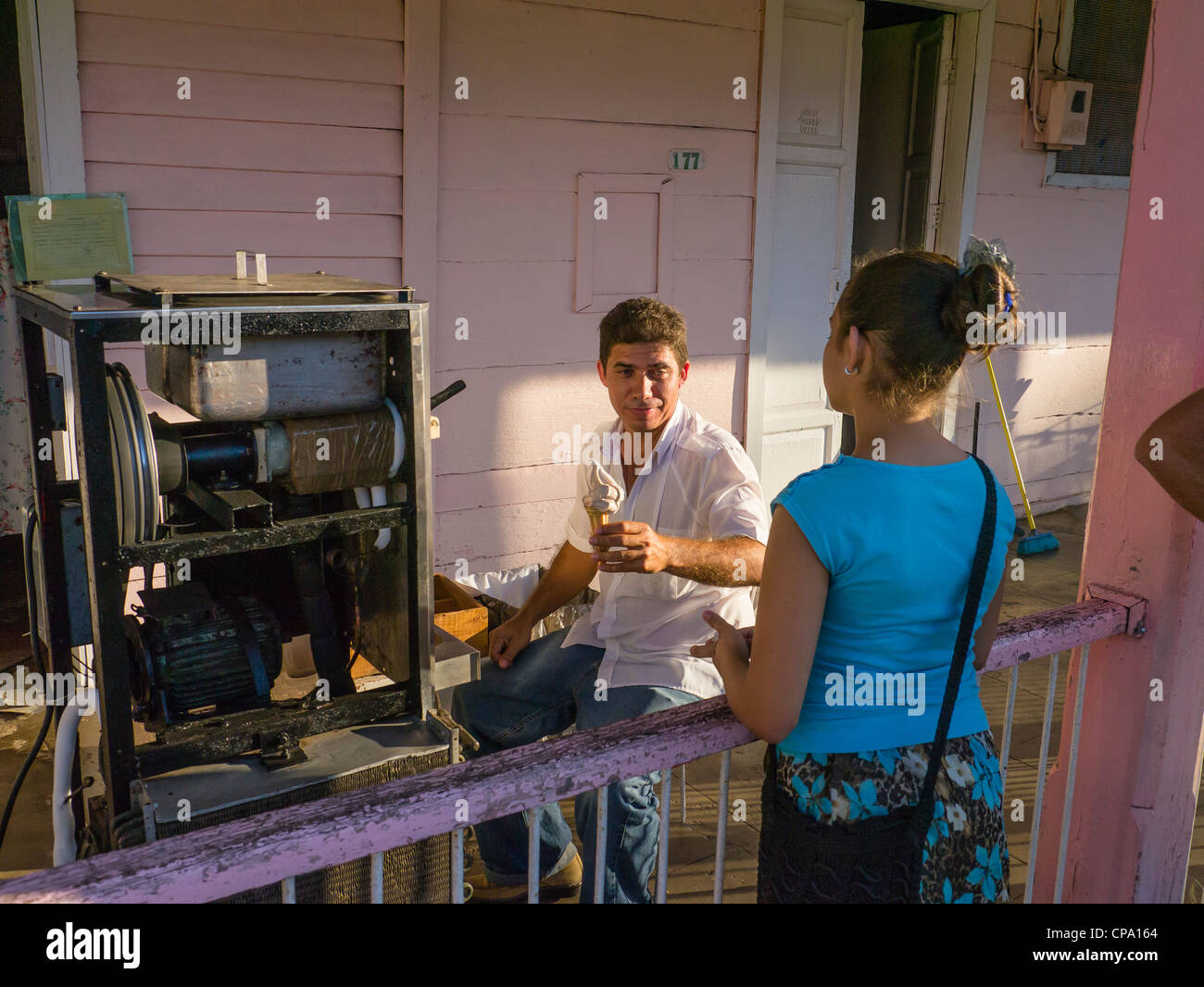 Ein Mann, der ein Haus Geschäft verkaufte Eis aus seiner Veranda in Viñales, Kuba betreibt verkauft einen Kegel mit einer Mädchen. Stockfoto