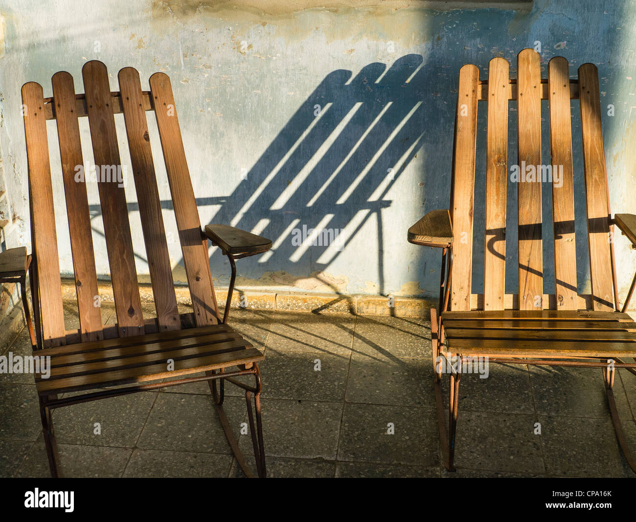 Lange Schatten von zwei Stühle mit Holzlatten platziert auf der Veranda eines kubanischen Hauses in Viñales, Kuba gemacht. Stockfoto