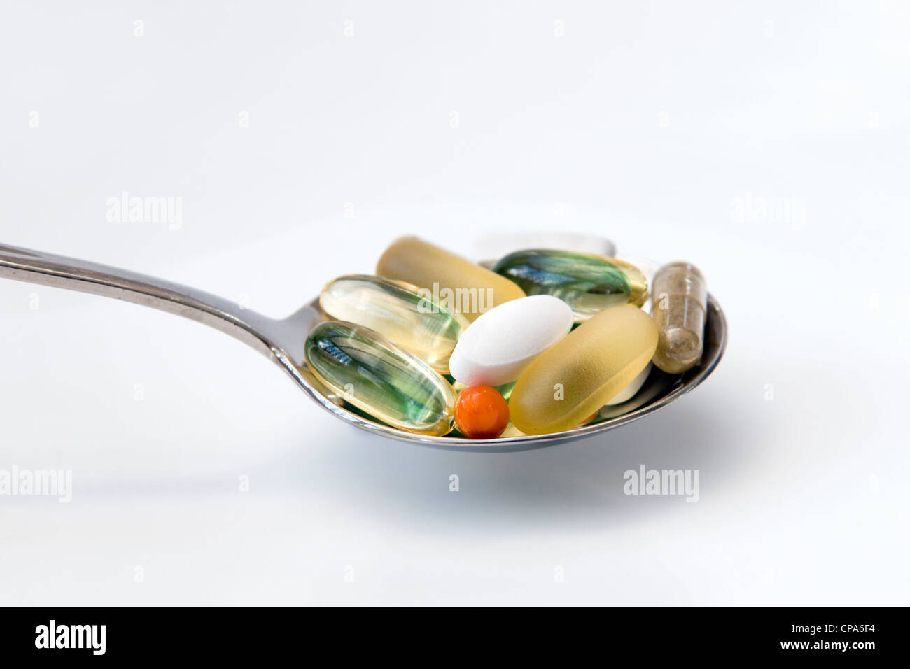 Auswahl an Vitaminen (Omega-3, Co-Enzym Q10, Pfefferminze, Chondroitin, Ginkgo und Ginseng) auf Löffel auf weißem Hintergrund. Stockfoto