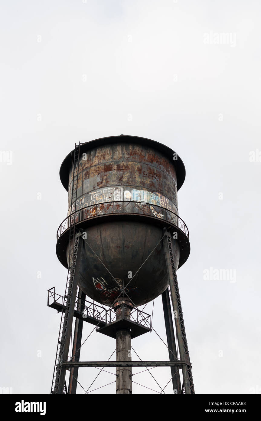 Ein alter Wasserturm mit Rost und Graffiti bedeckt. Stockfoto