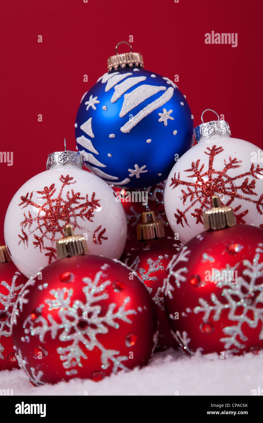 bunte Weihnachtskugeln über den Schnee mit einem roten Hintergrund (Tiefenschärfe) Stockfoto