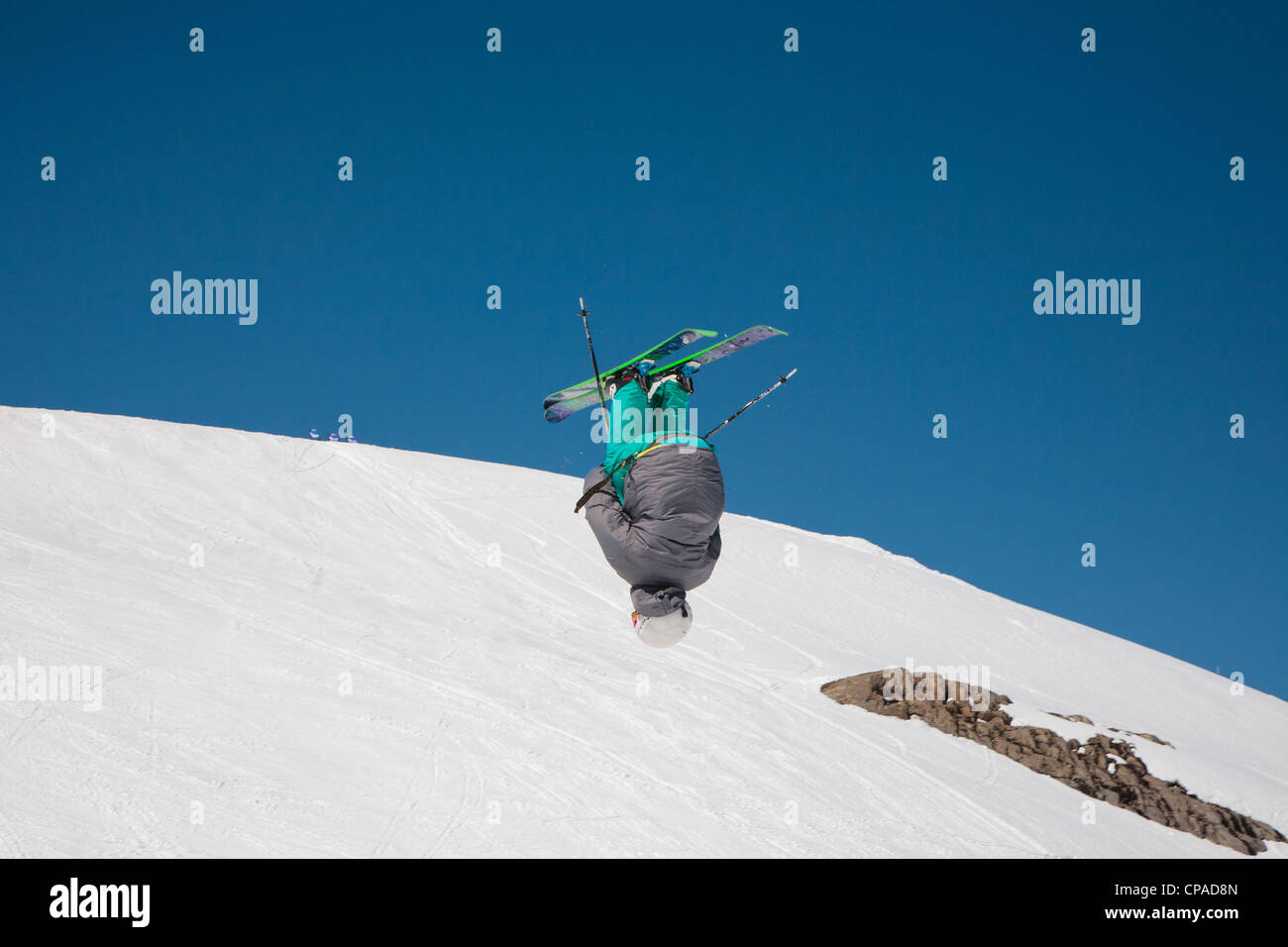 Ein Freestyle-Skifahrer führt einen Salto in der Luft auf einem verschneiten Hintergrund. 2 von 2. Stockfoto