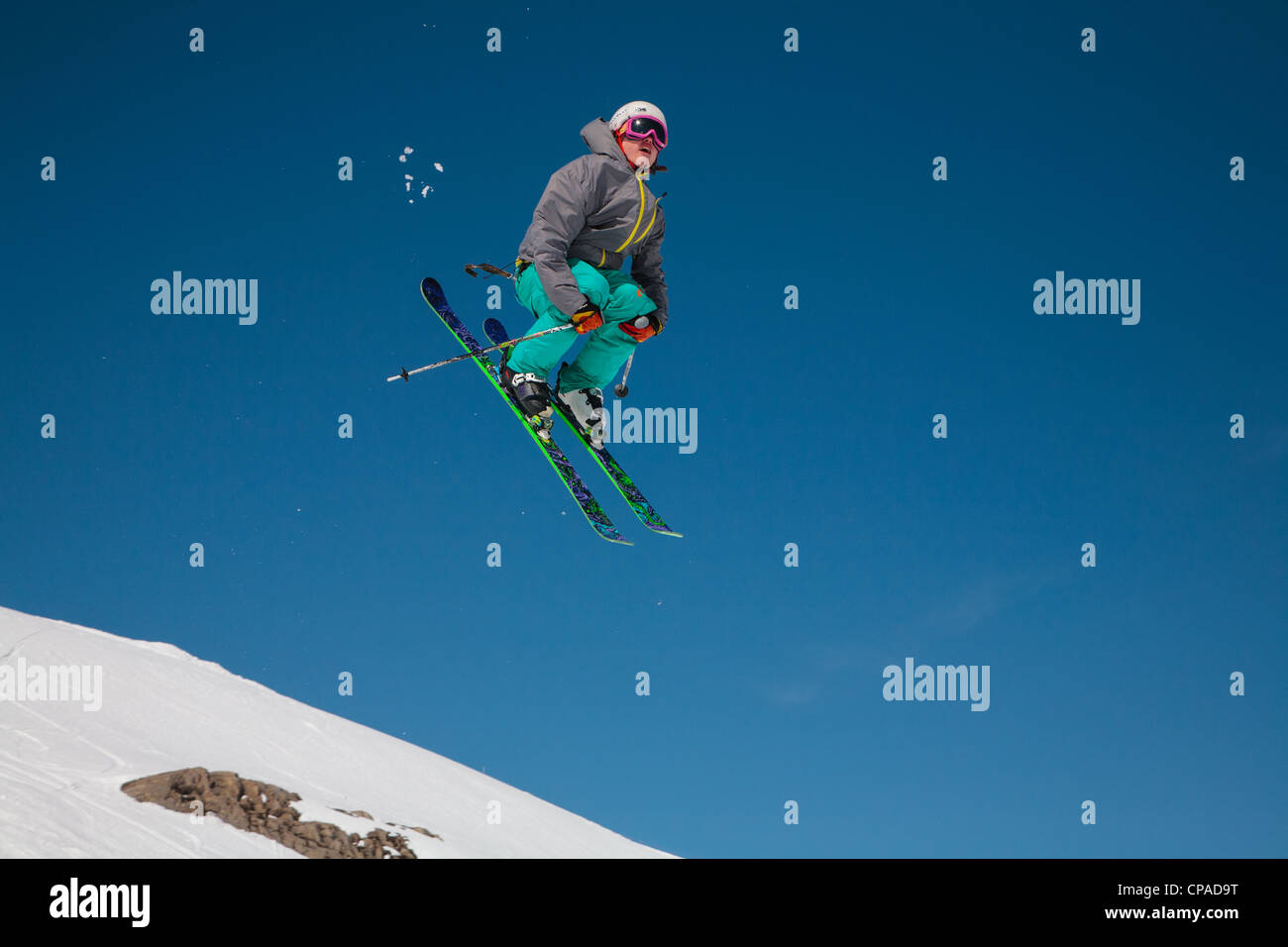 Ein Freestyle-Skifahrer führt einen Salto in der Luft vor einem strahlend blauen Himmel. 1/2. Stockfoto