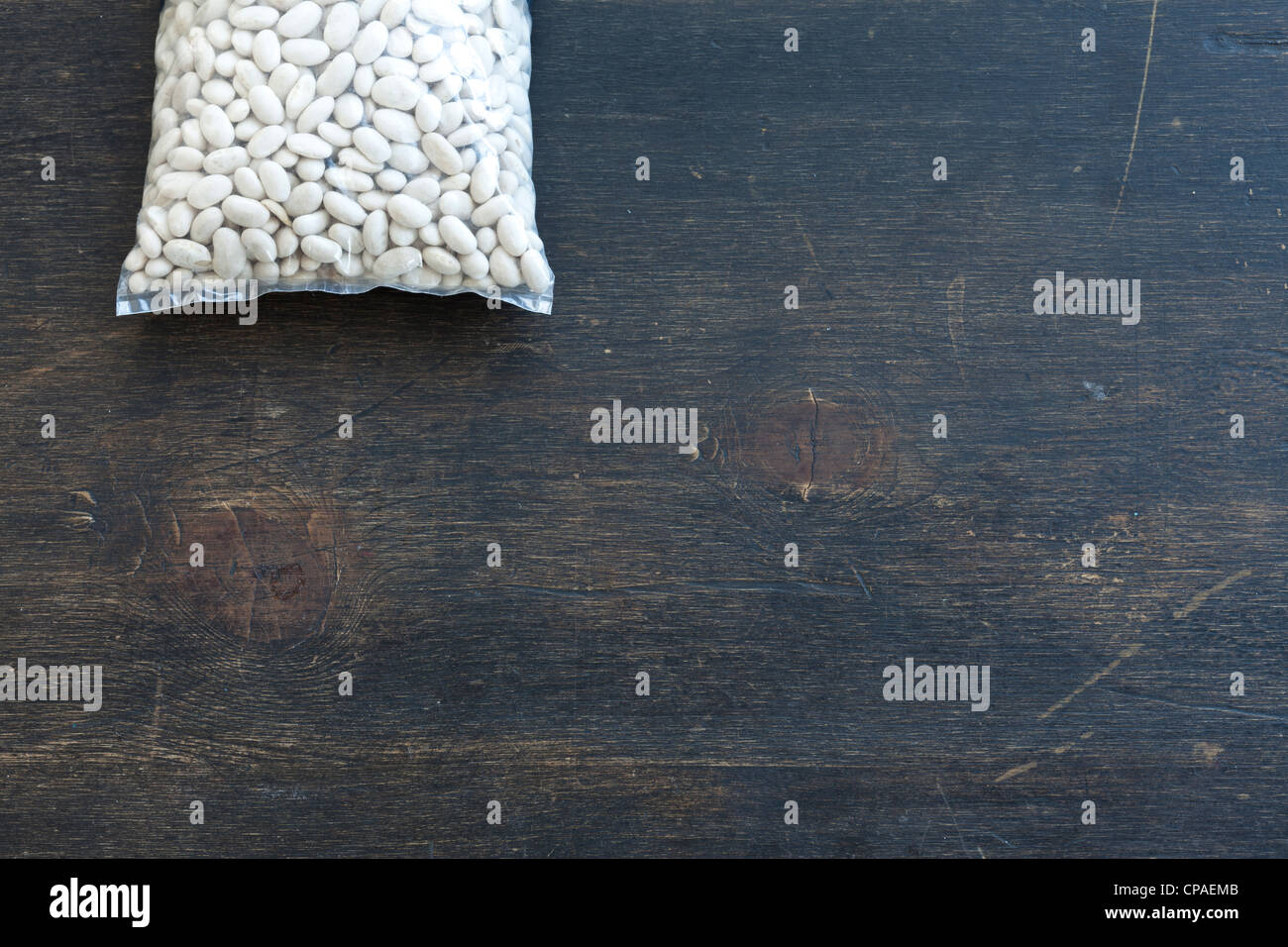Plastiktüte mit trockenen Bohnen auf Holztisch Stockfoto
