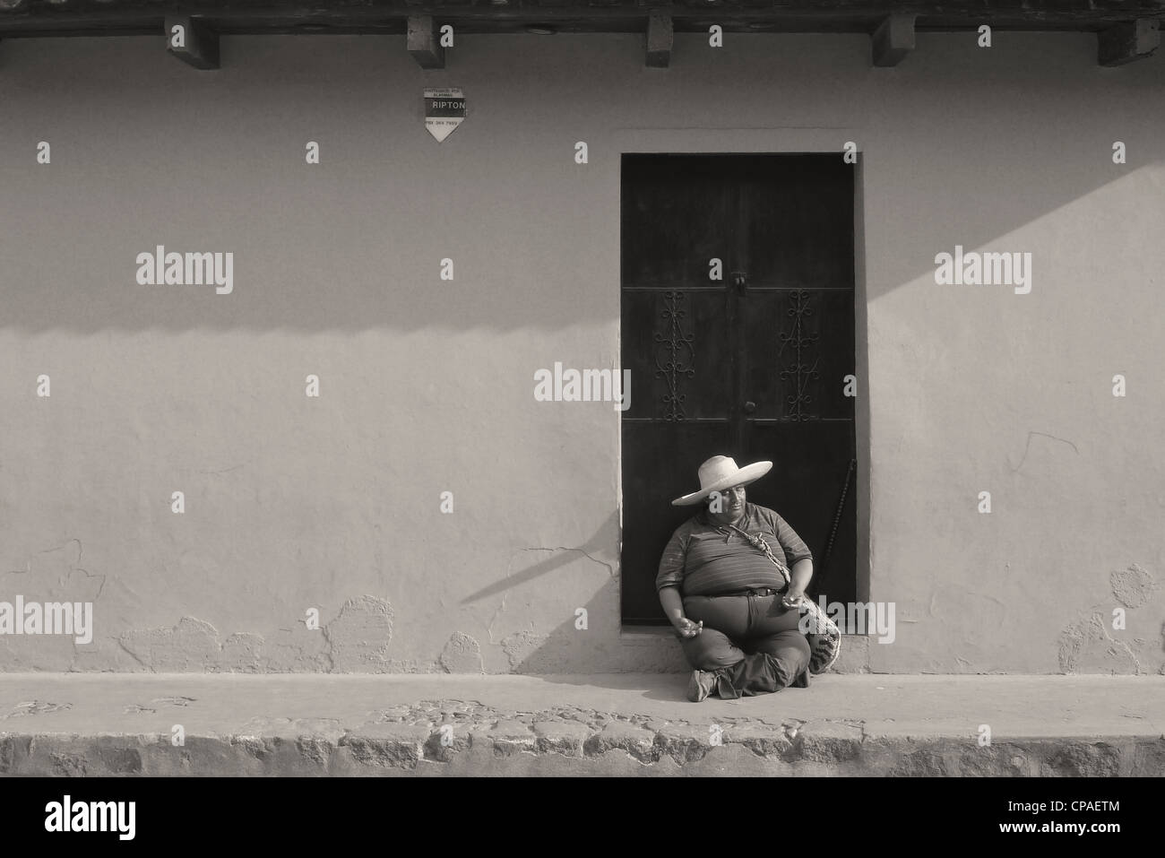 Guatemala Antigua Mann mit Sombrero-Hut sitzt durch bunte Wand cobble stone Straßenszene der UNESCO Stockfoto