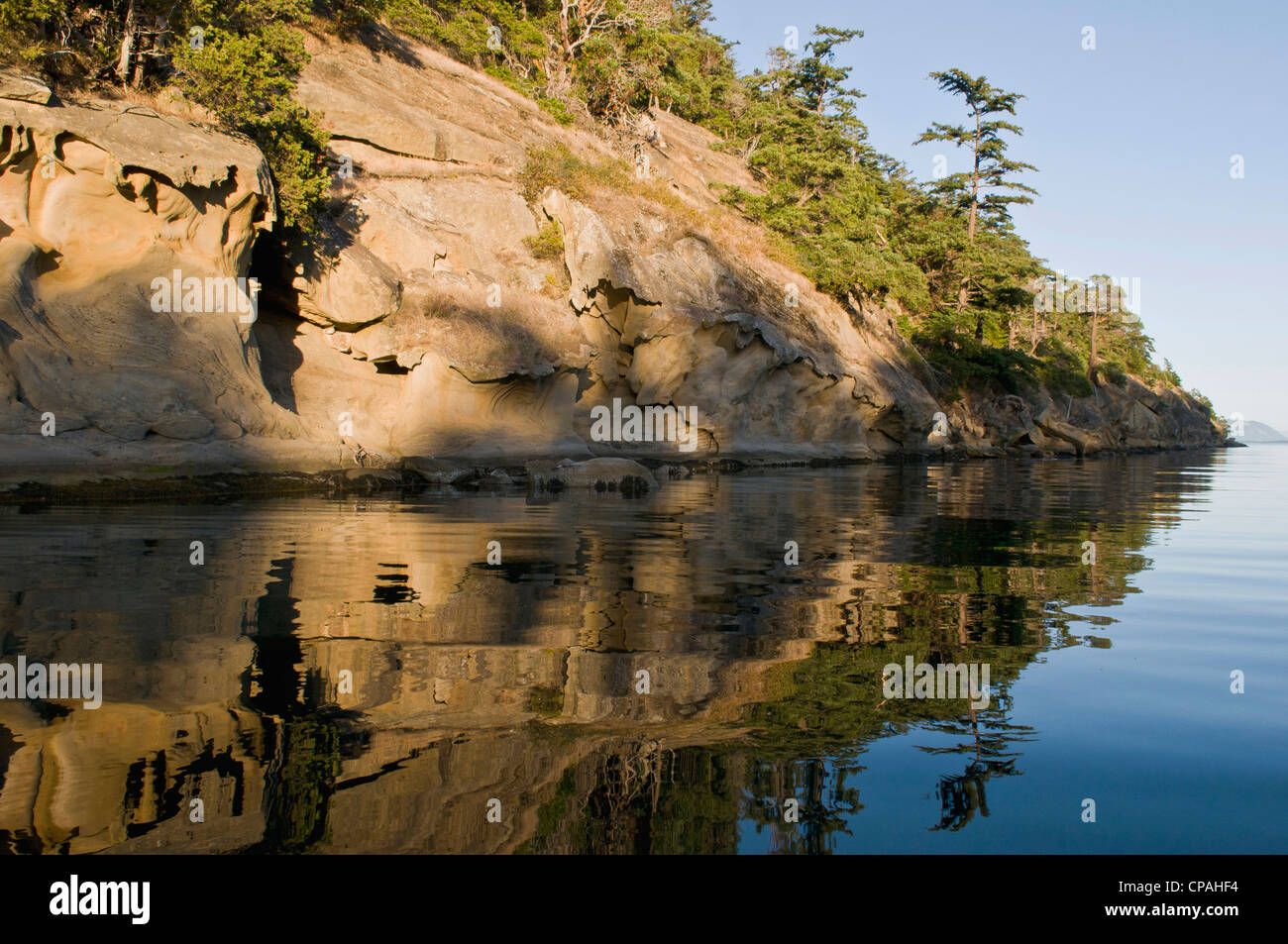 USA, WA, San Juan Inseln. Erodierte Sandstein-Klippen Sucia Insel zu reflektieren, in ruhigem Wasser Stockfoto