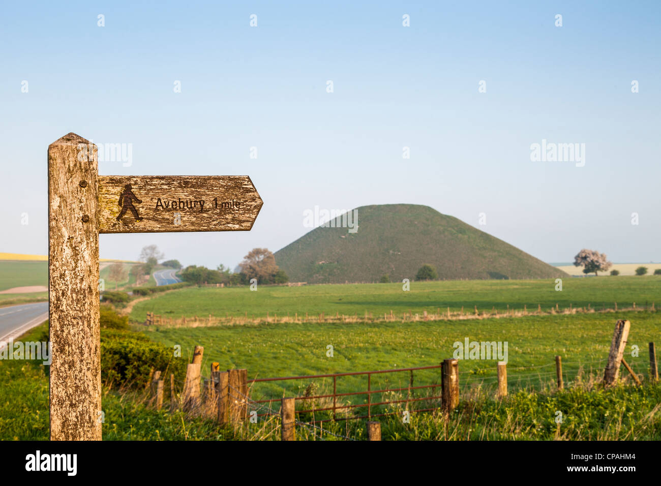Wegweiser für Fußweg nach Avebury in Wiltshire, mit Silbury Hill, ein neolithischer Monument im Hintergrund. Stockfoto