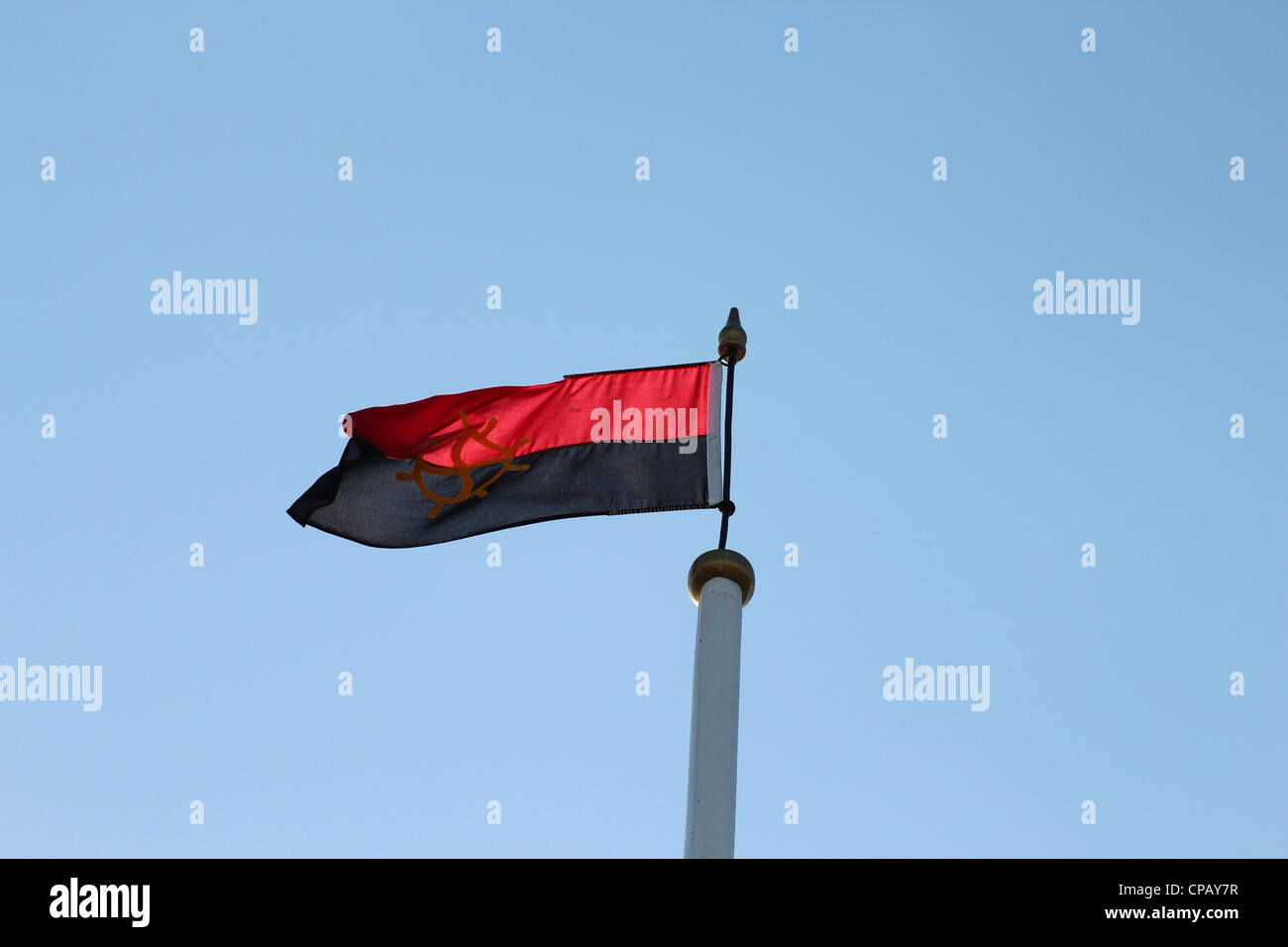 Eine rote und schwarze Flagge auf dem Gipfel ein Schiffsmast flattern im Wind. Stockfoto