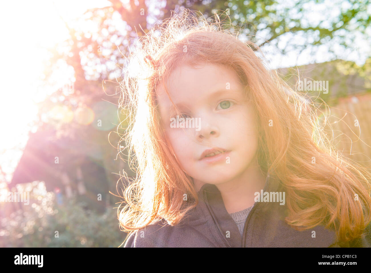Kleines Mädchen mit Ingwer Haar sieht Kamera in ihrem Sommergarten Stockfoto
