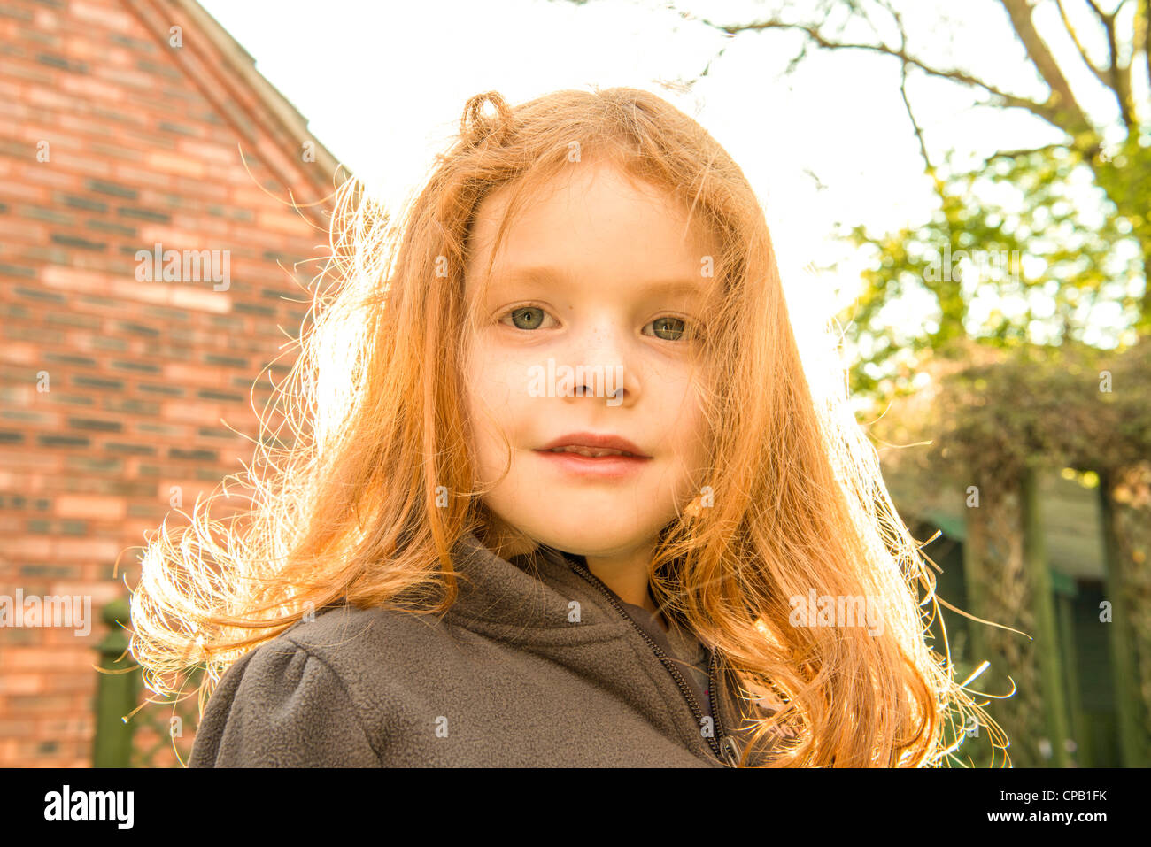 Kleines Mädchen mit Ingwer Haar sieht Kamera in ihrem Sommergarten Stockfoto