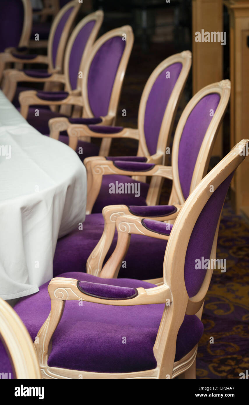 Einige luxuriöse lila Stühle aufgereiht in eine formale Esszimmer. Stockfoto