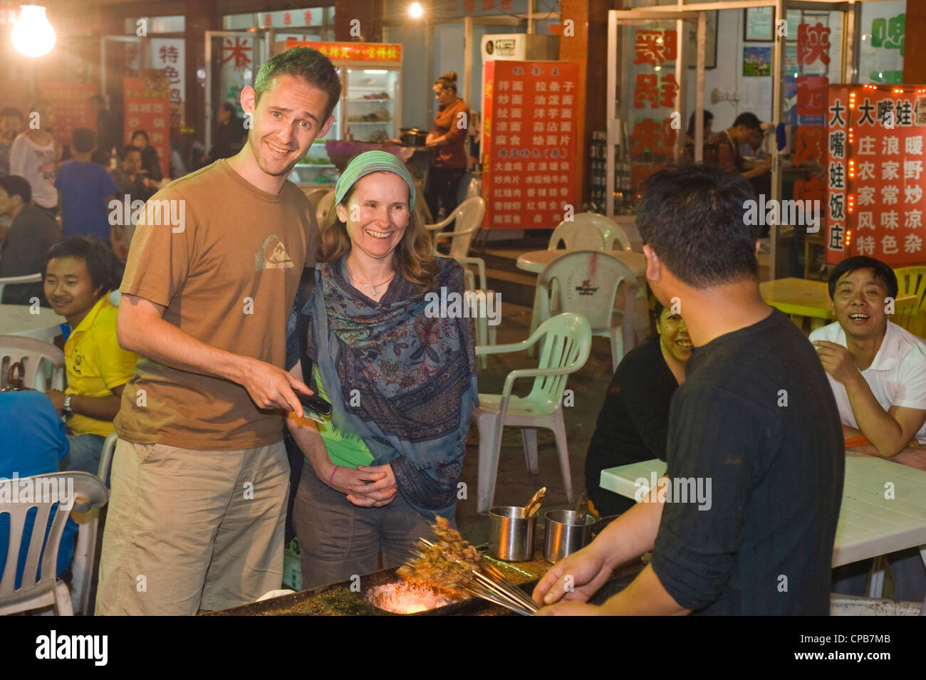 2 Europäische Touristen kaufen Essen von einem Anbieter von Outdoor-Straßenmarkt in Pingliang. Stockfoto