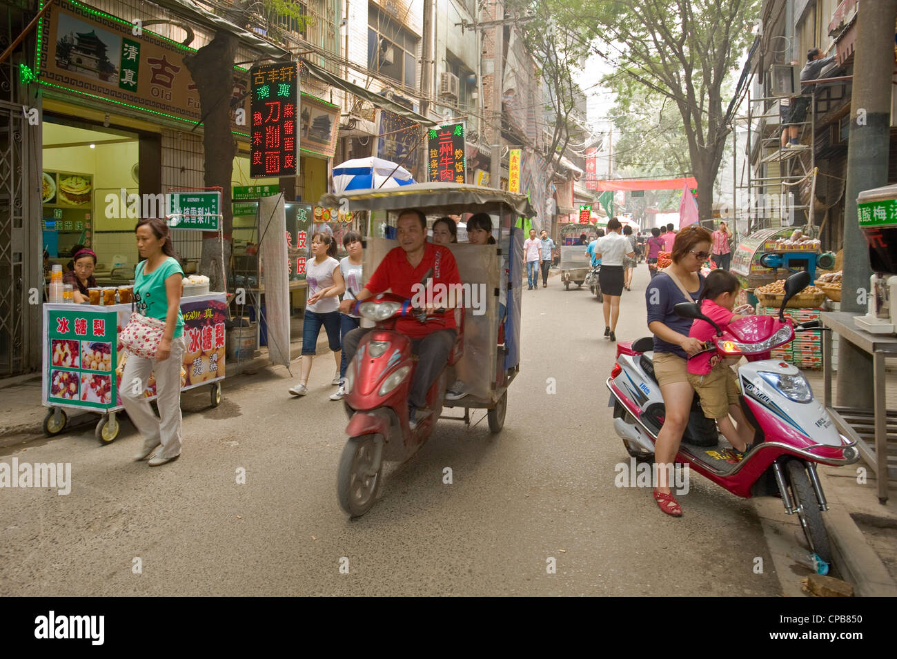 Eine typische Straßenszene der lokalen chinesischen gehen über ihr tägliches Geschäft in einer Seitenstraße im moslemischen Viertel von Xian. Stockfoto