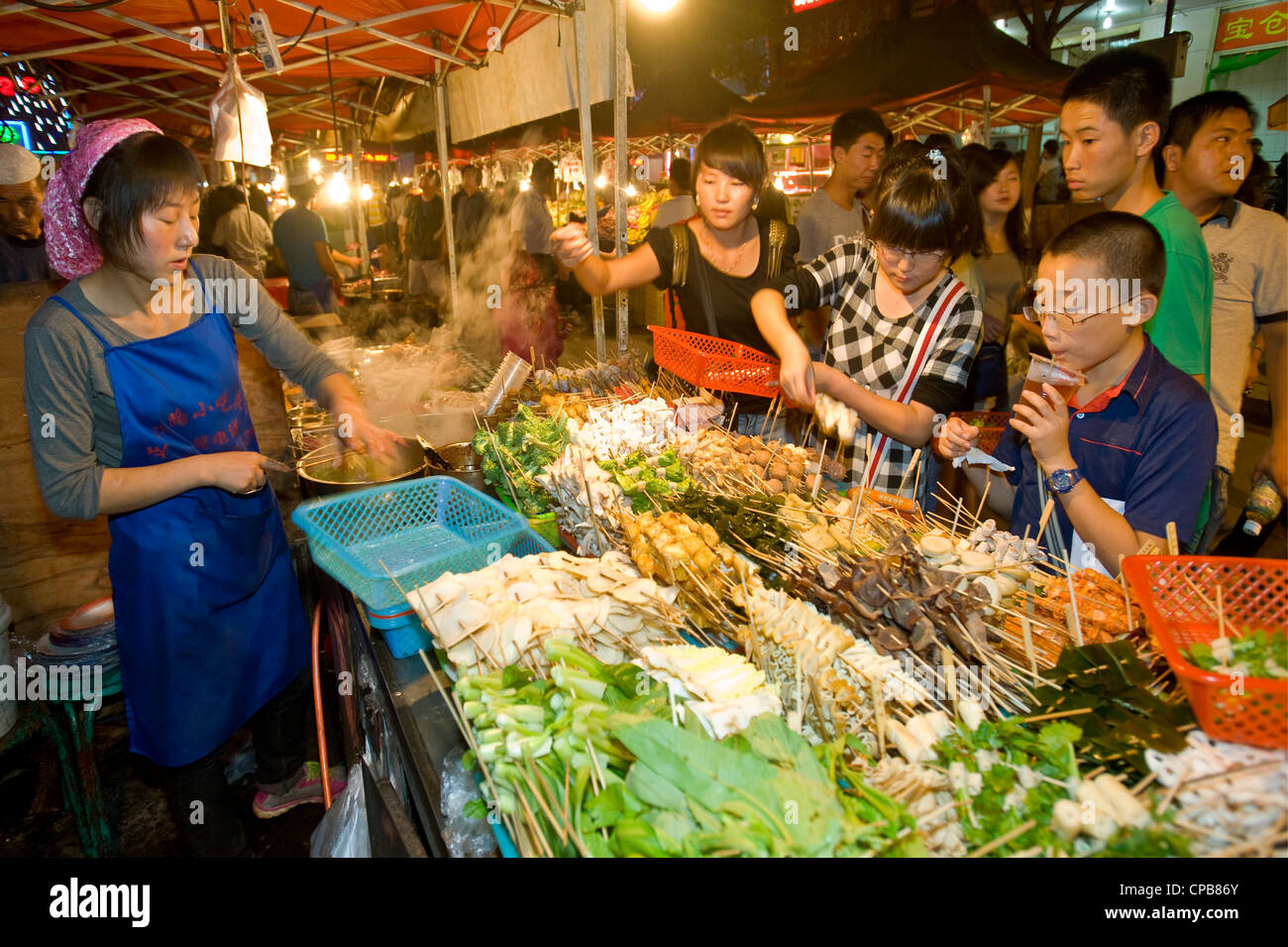 Eine Chinesin verkaufen Snacks auf dem bekannten Zhengning Straße Essen street Nachtmarkt in Lanzhou. Stockfoto