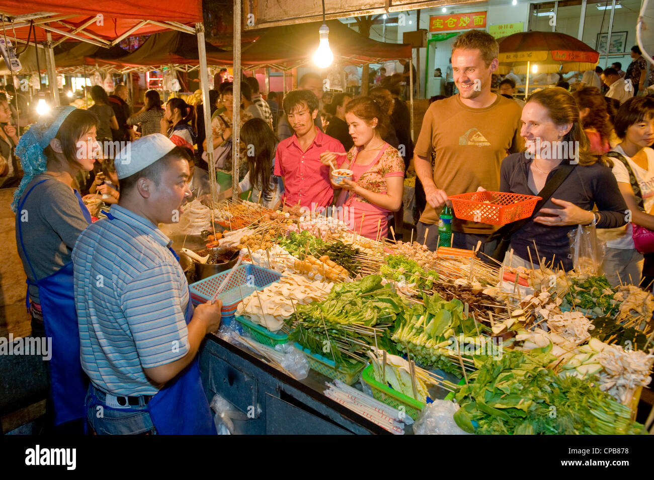 2 Europäische Touristen kaufen Snacks auf dem bekannten Zhengning Straße Essen street Nachtmarkt in Lanzhou. Stockfoto