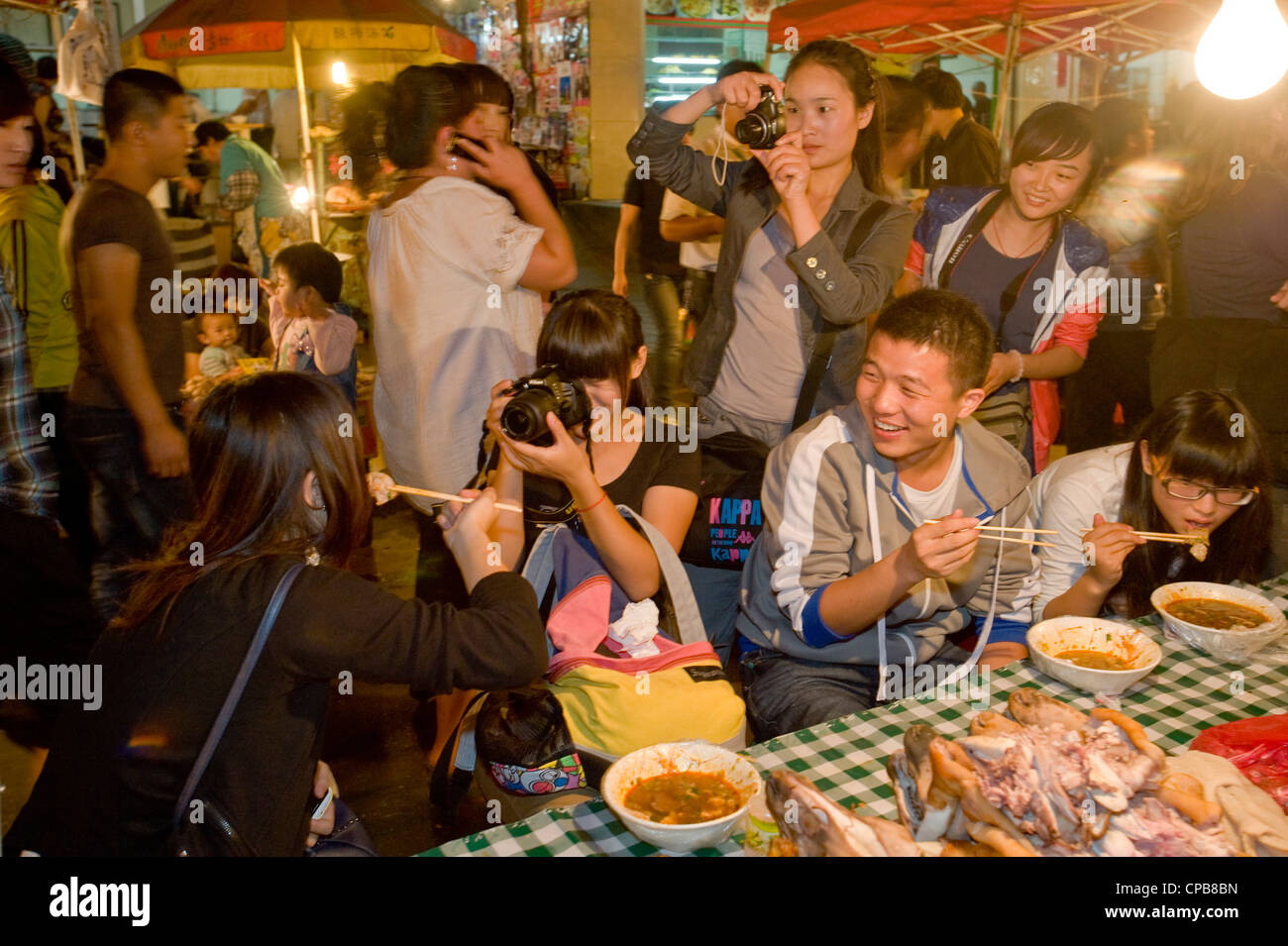 Eine Gruppe von jungen Chinesen Spaß fotografieren und Essen auf dem bekannten Zhengning Straße Nahrung Straße Nachtmarkt Stockfoto