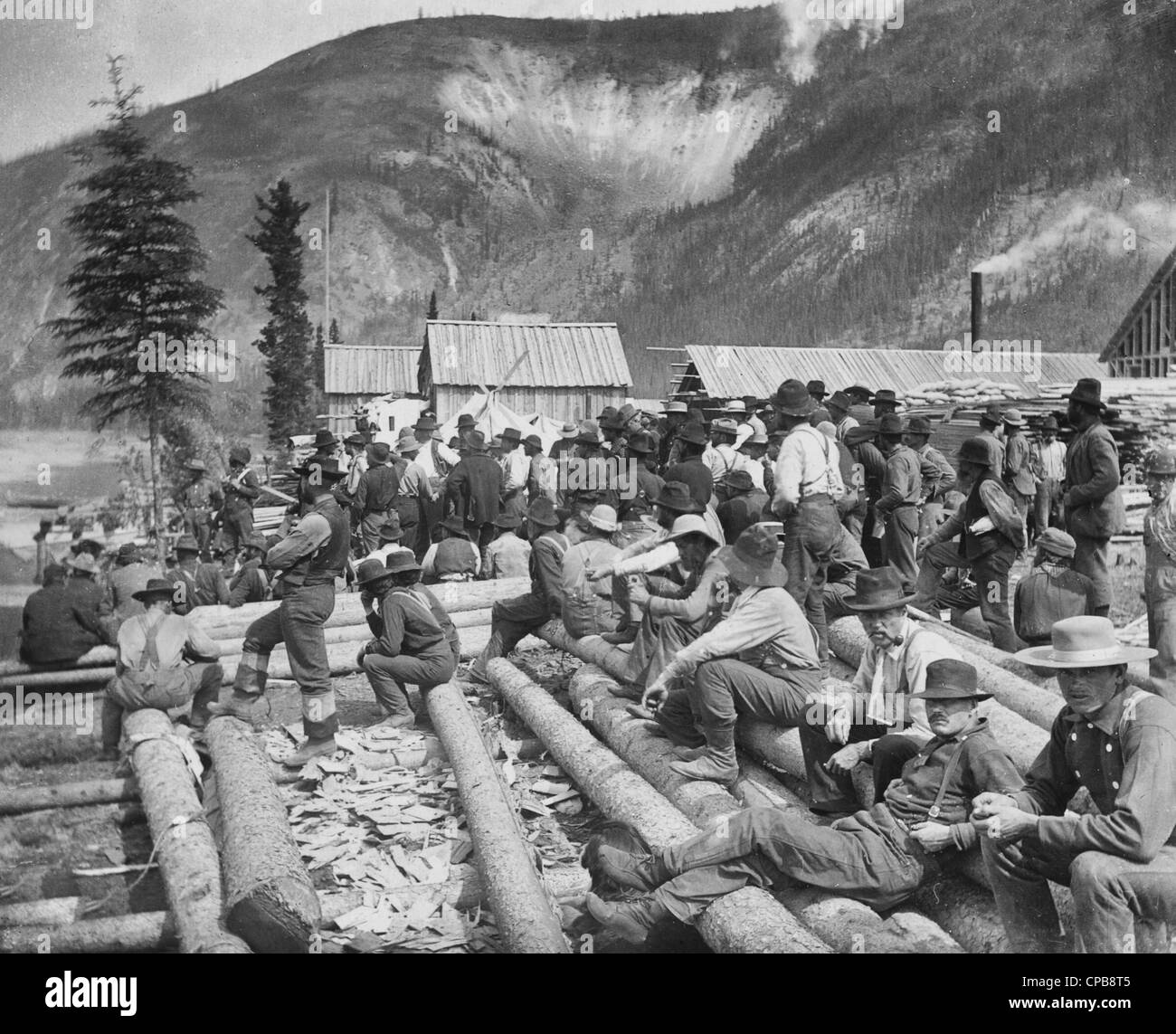 Warten auf den Dampfer - große Gruppe von Goldgräber auf Protokolle, sitzend warten auf einem Dampfer, Dawson City, Yukon Territory, ca. 1897 Stockfoto