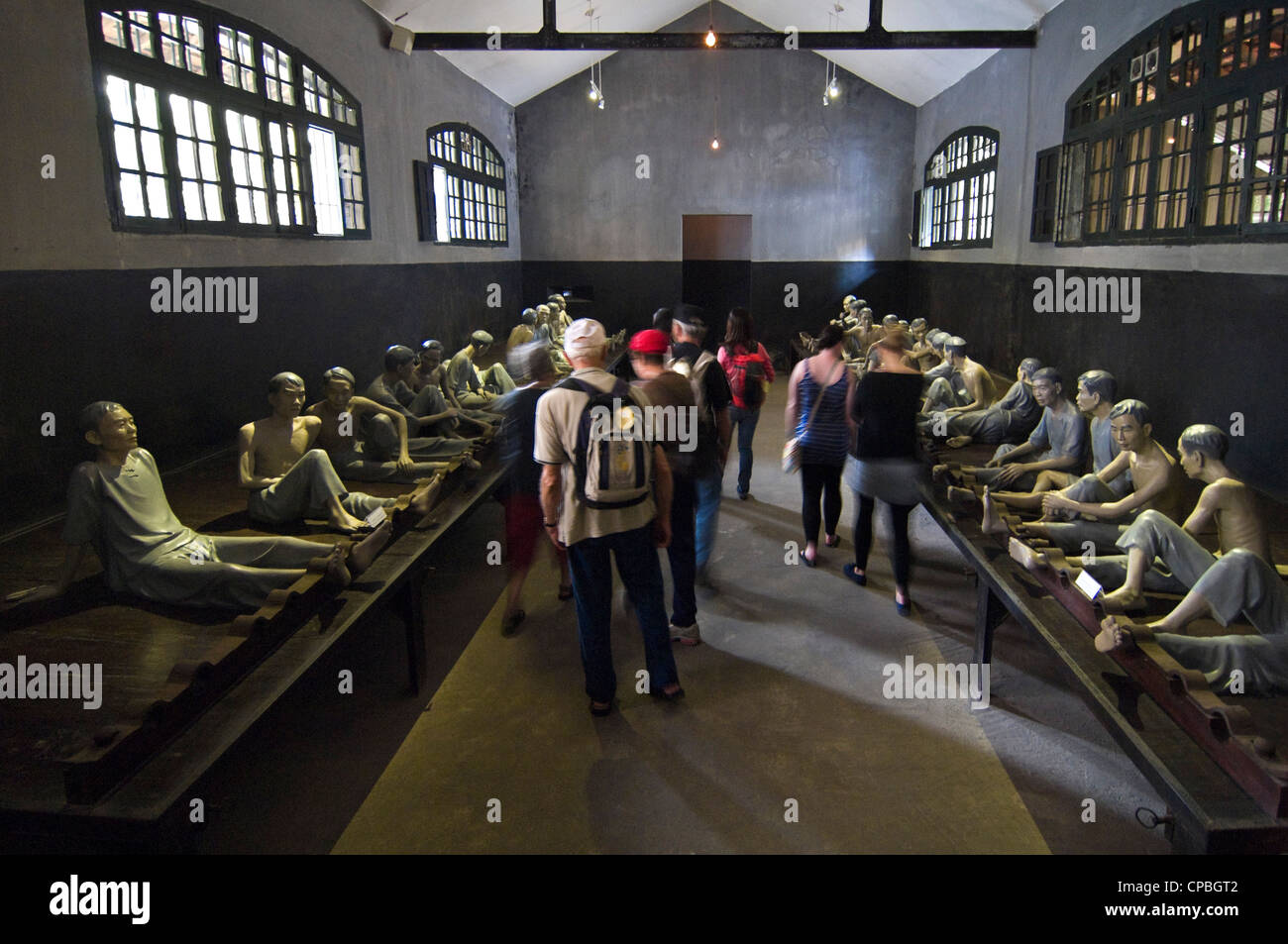 Horizontale Ansicht der Touristen innerhalb eines alten Zelle bei Hoa Lo Prison Museum aka Hanoi Hilton, mit einer Darstellung von Gefangenen in Fesseln, in Hanoi, Vietnam Stockfoto