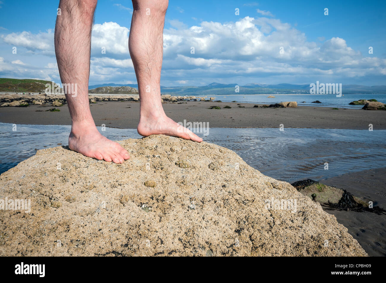 Mann, der barfuß auf Felsen am Strand Küste Stockfoto