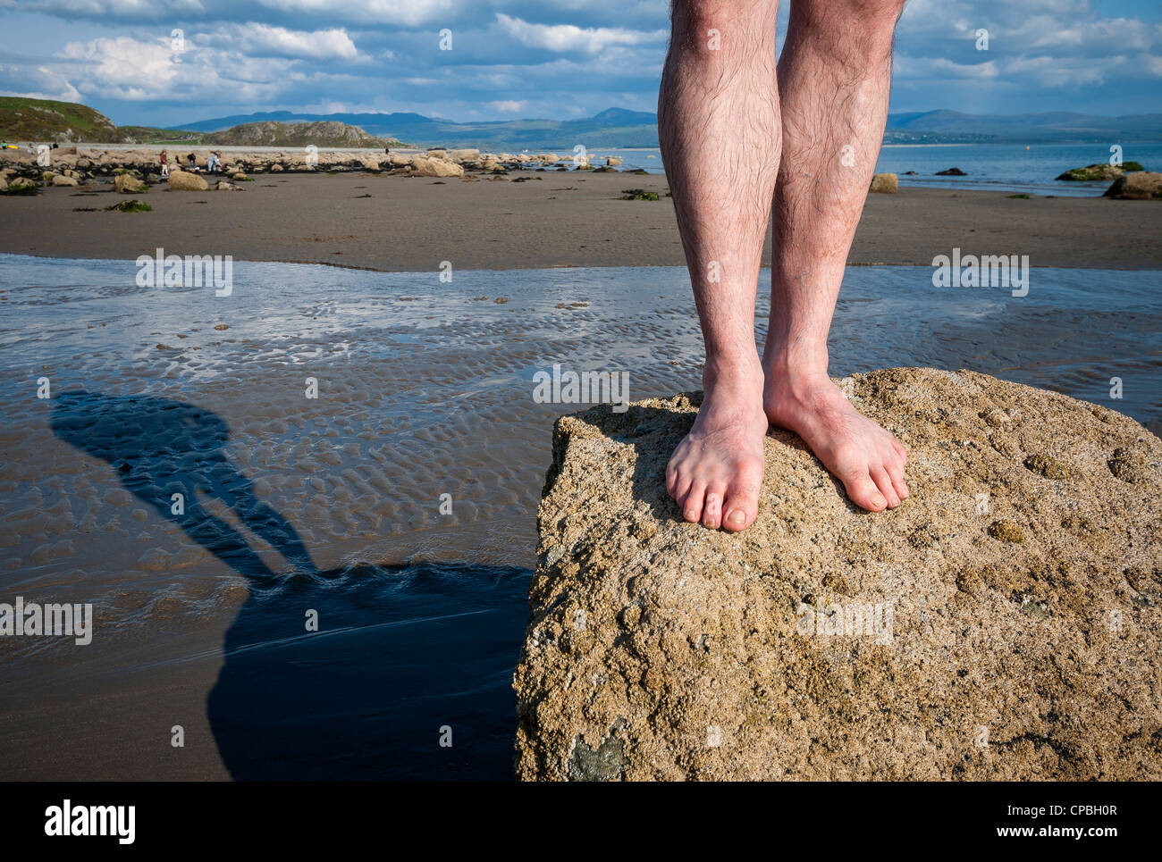 Mann, der barfuß auf Felsen am Strand Küste Stockfoto